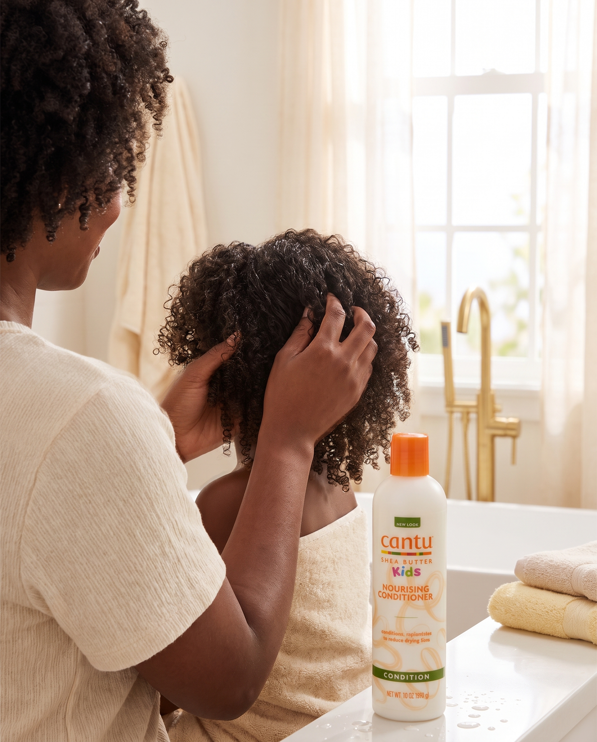 Mutter entwirrt die Locken ihrer Tochter mit dem Cantu Kids Conditioner